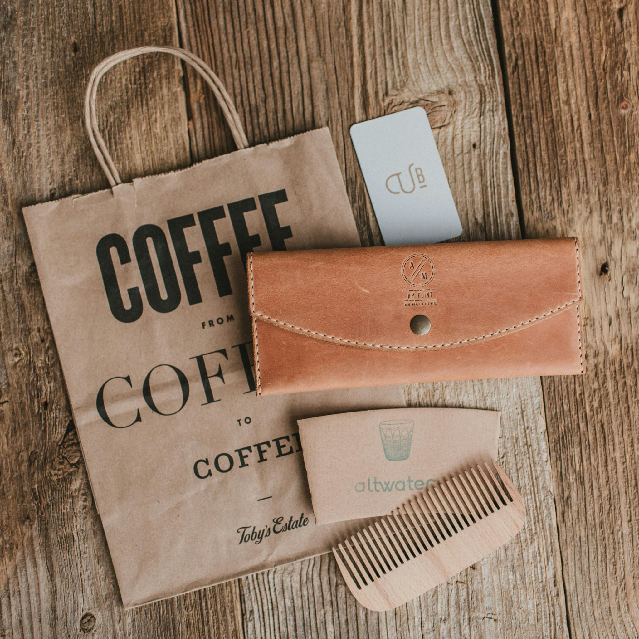 Eco-friendly lifestyle items including a leather wallet, wooden comb, and coffee bag.